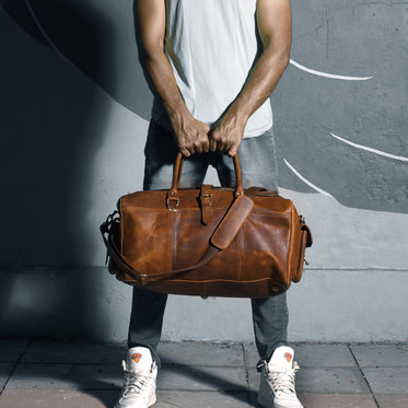 man holding his leather travel bag