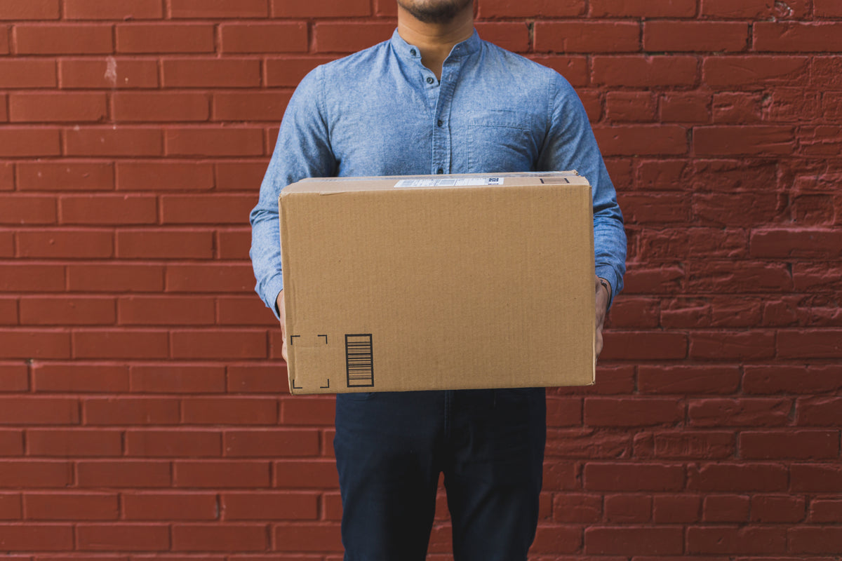 man holding shipping box on red brick