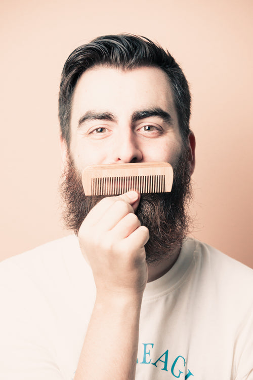 man holds a comb up to his mustache