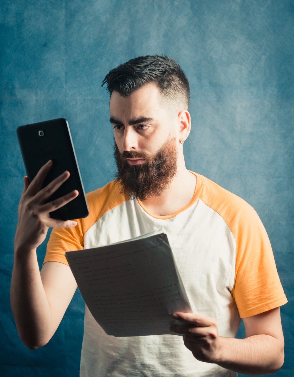 man holds a phone and a stack of white paper