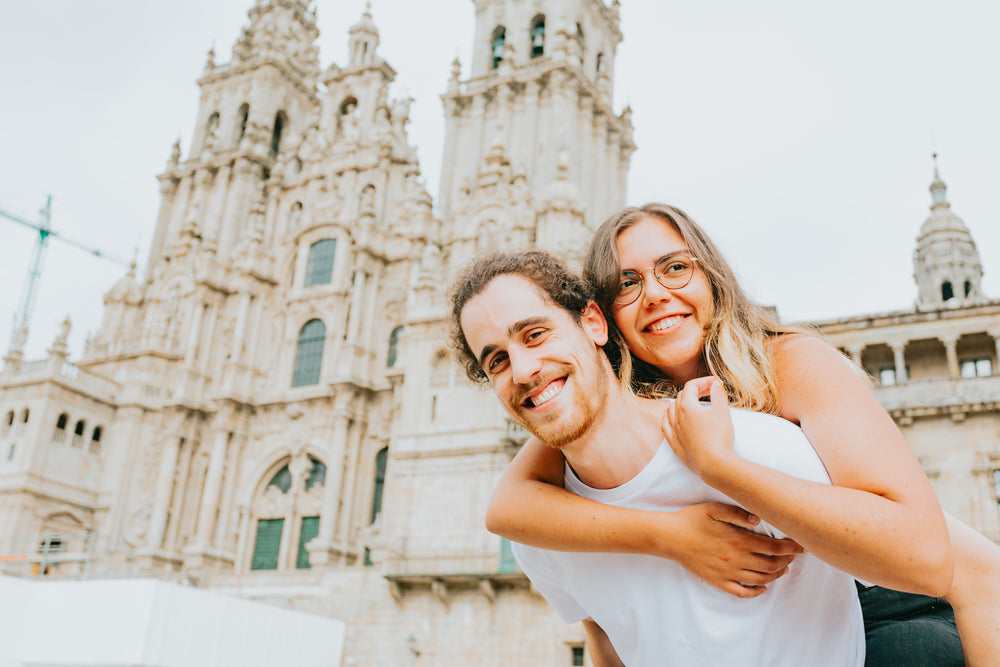 man holds woman up on his back as they both smile