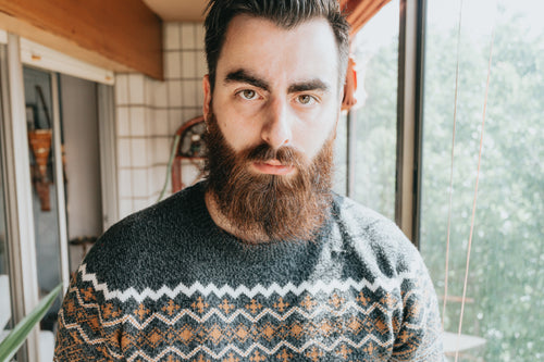 man in a grey sweater looks into the camera