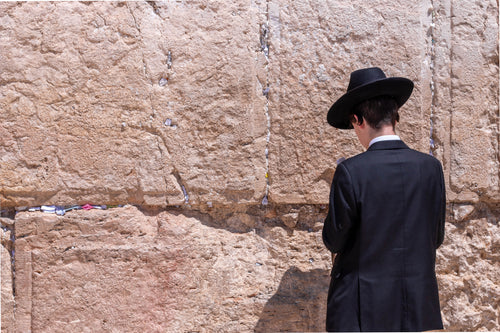 man in black in front of wailing wall