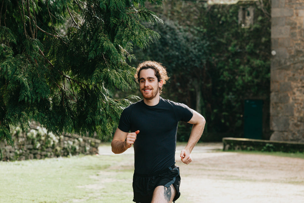 man in black out for a run through green trees