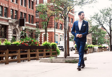 man in blue suit walking in the city