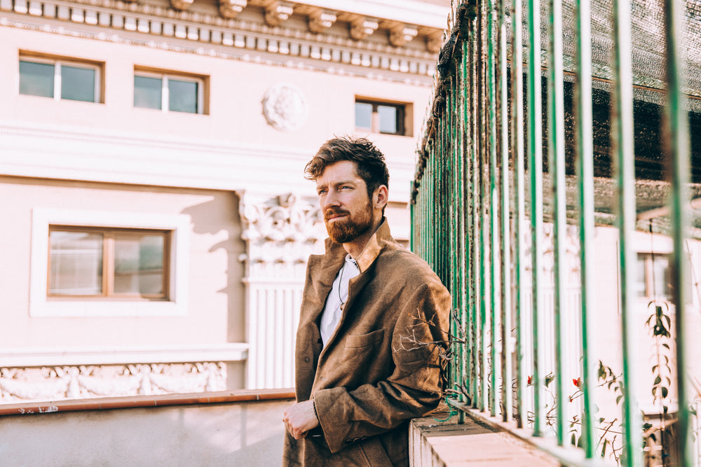 man in coat leans against railing