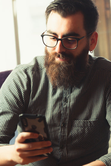 Man In Green Looks At His Cell Phone