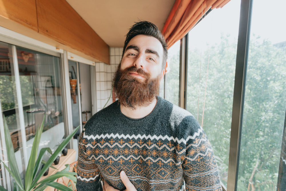 man in grey and orange softly smiles at the camera