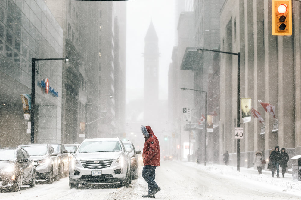 man in red parka crossing in front of traffic