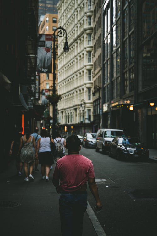 man in red t-shirt walks through city