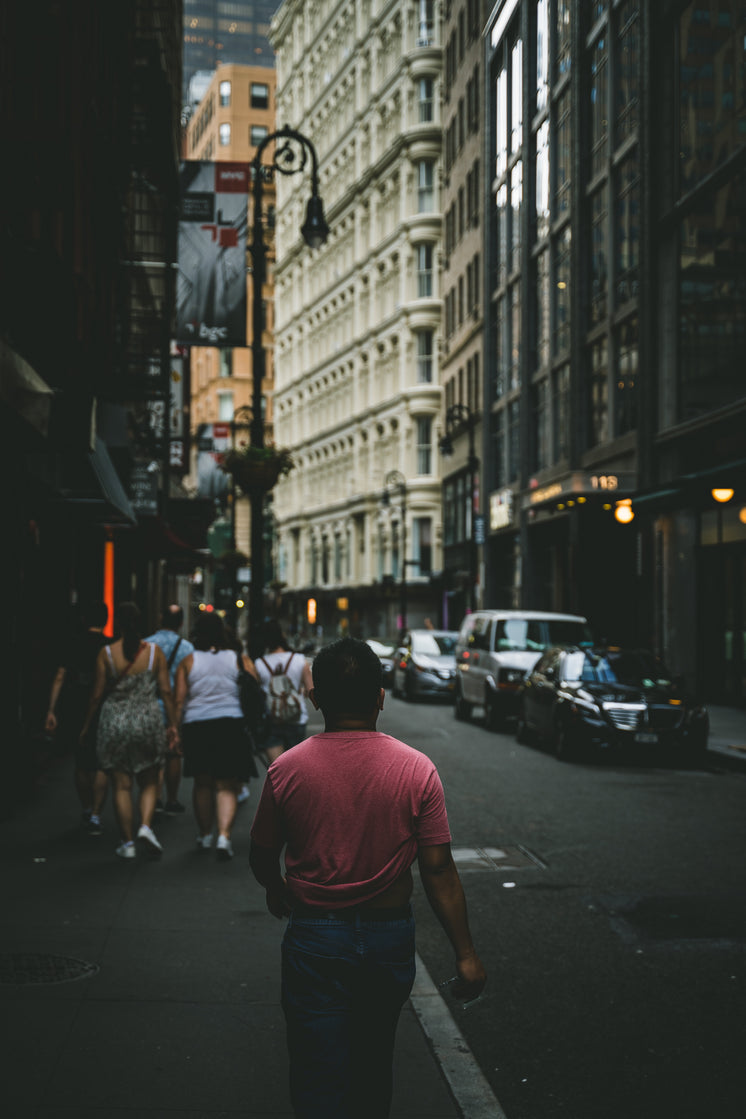 Man In Red T-Shirt Walks Through City