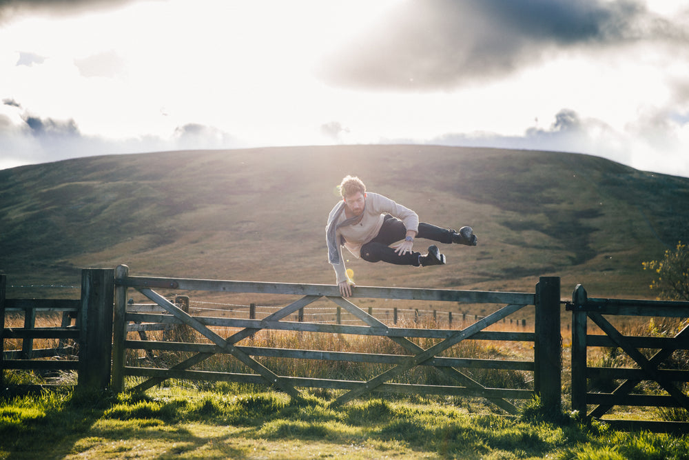 man jumping fence by field