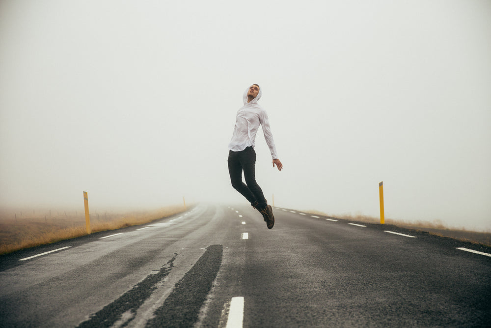 homem dando um pulo em uma estrada