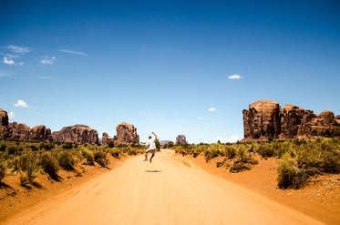 man jumps on desert road