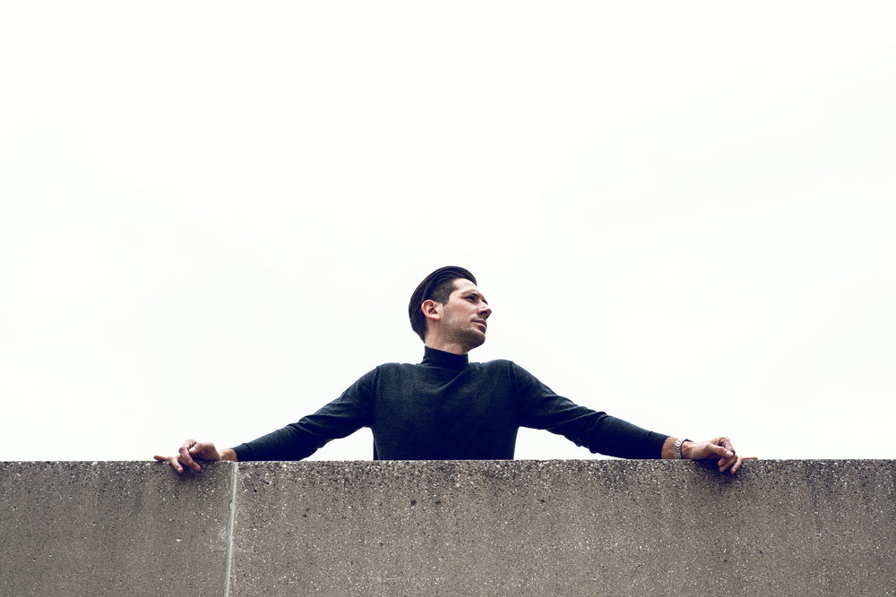 man leans over wall in urban setting