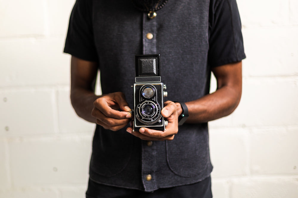 man lines up frame with vintage camera