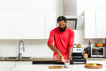 man makes pour over coffee in kitchen