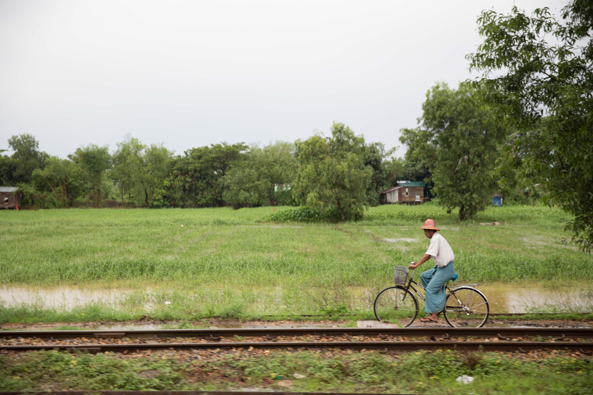 homem de bicicleta perto do trilho do trem