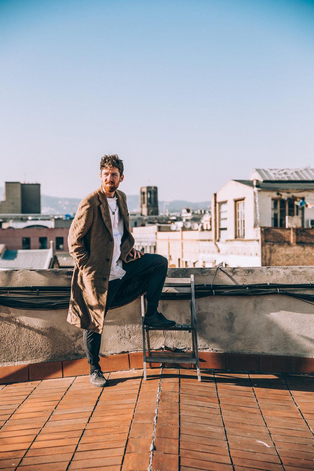 man on roof with one leg on chair