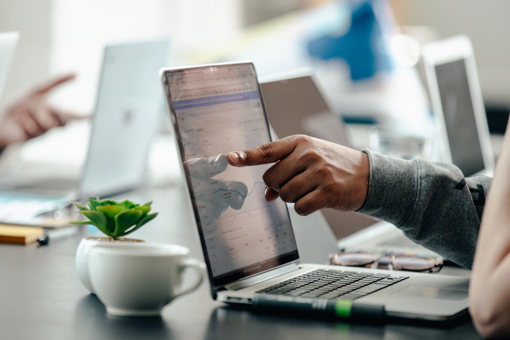 man pointing at laptop screen analytics