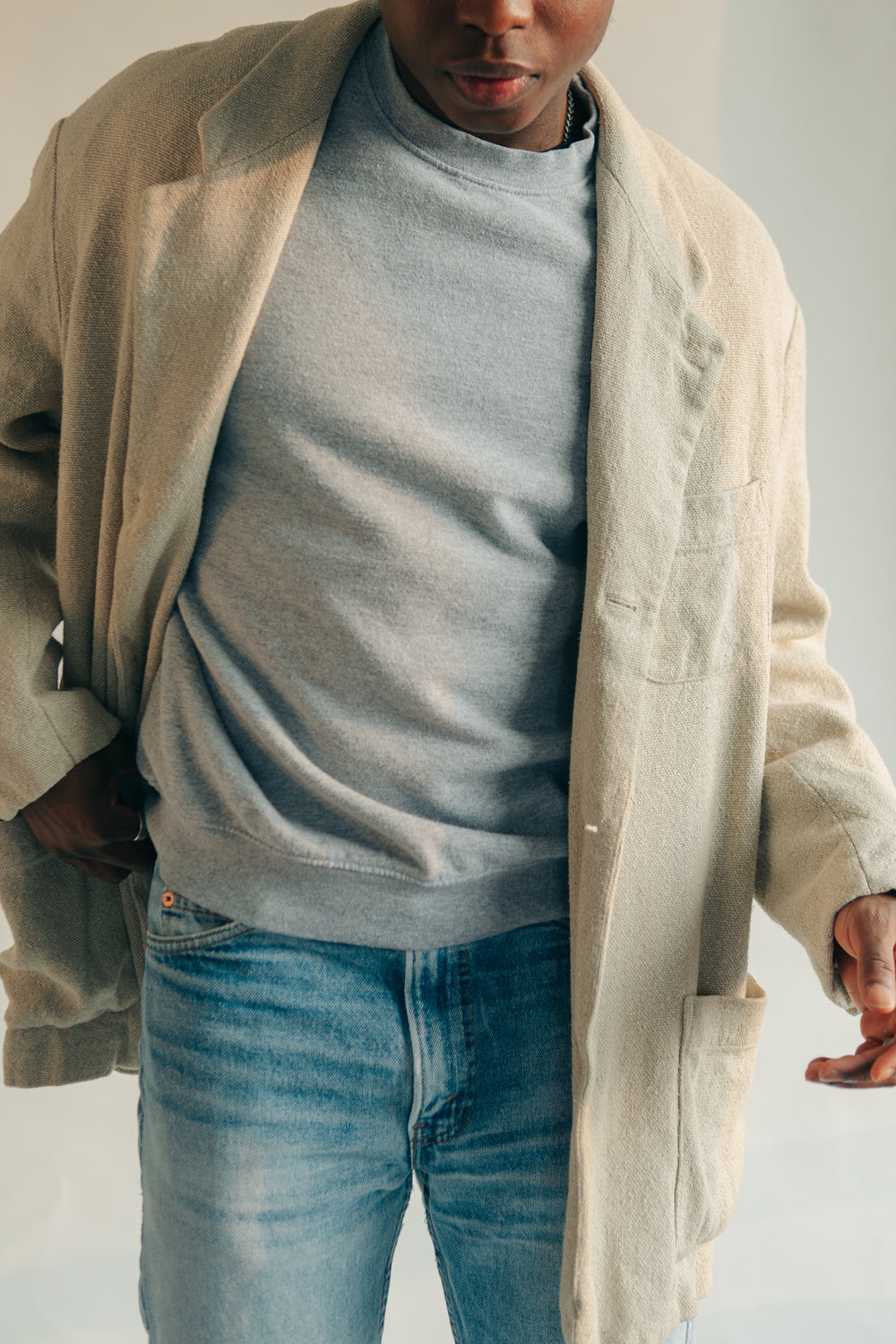 man poses in light colored overcoat