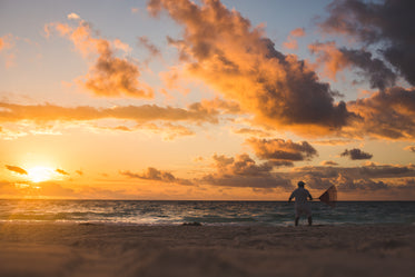 man raking beach at sunset