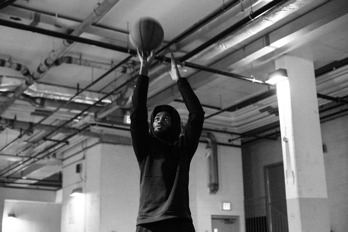 一个人把手伸向高处，用篮球投篮