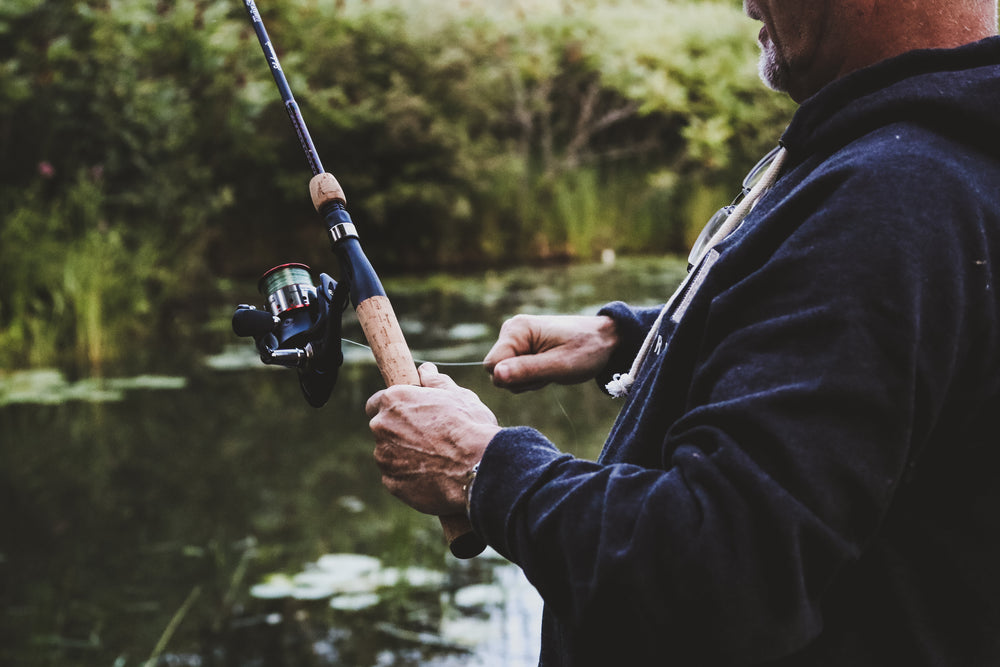 man reeling in on fishing rod