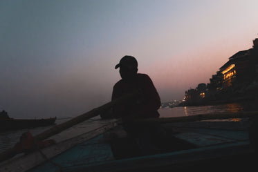 man rowing a boat at dusk