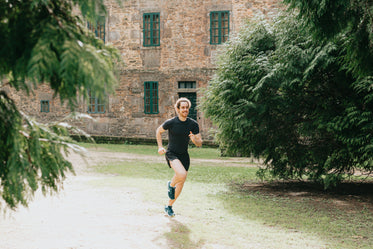 man runs outdoors with a stone building behind him