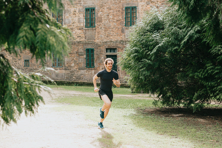 Man Runs Outdoors With A Stone Building Behind Him