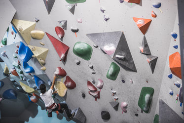 man scaling a rock climbing wall