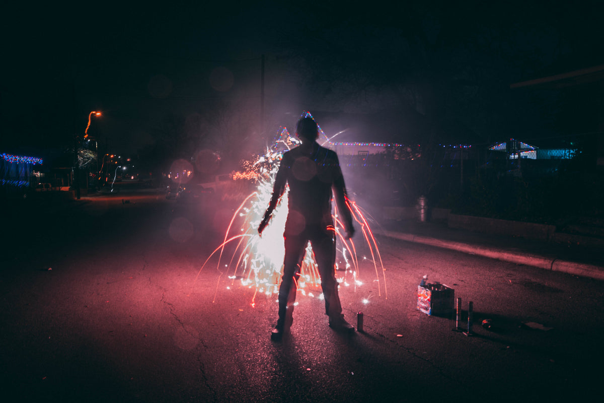 man setting off fireworks on suburban street
