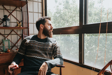 man sits in a chair and looks out the window