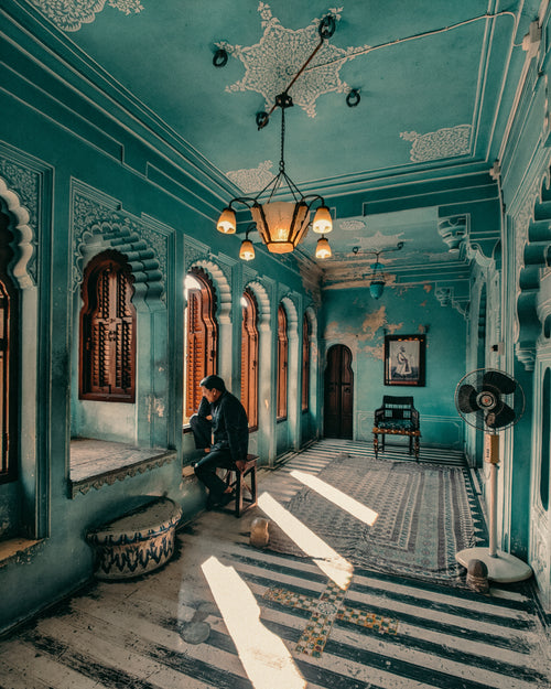 man sits within ornate blue hallway