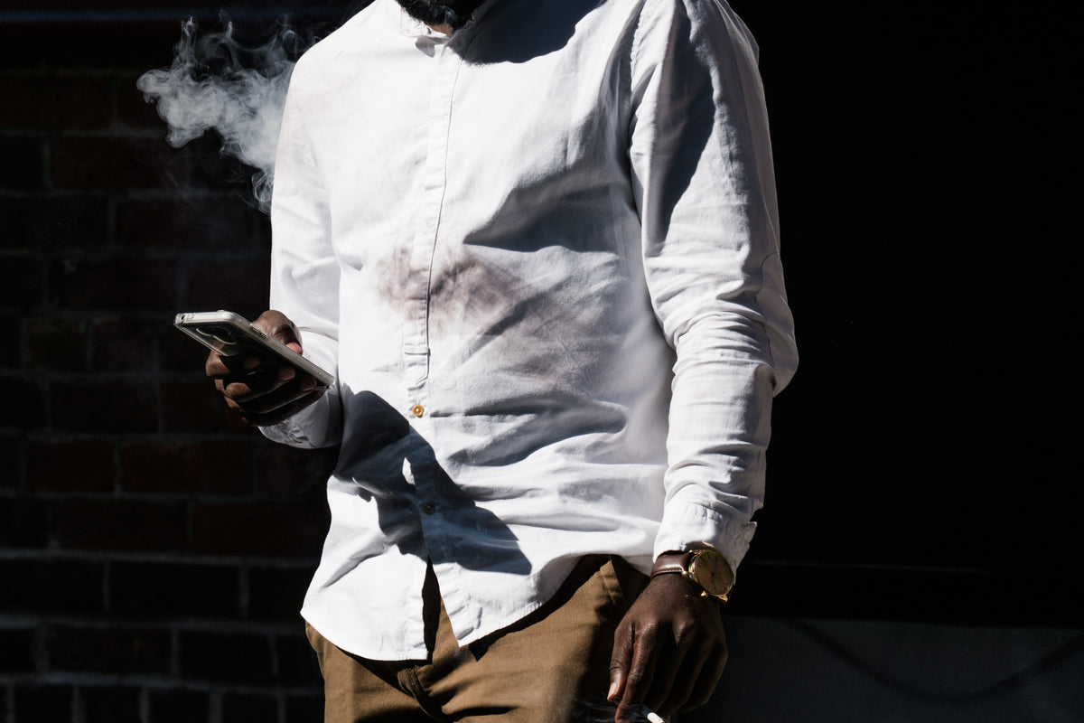 homem fumando e olhando o celular