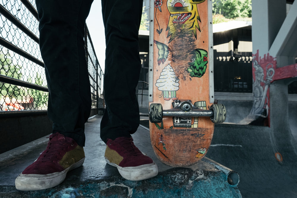 man stood with skateboard wearing worn sneakers