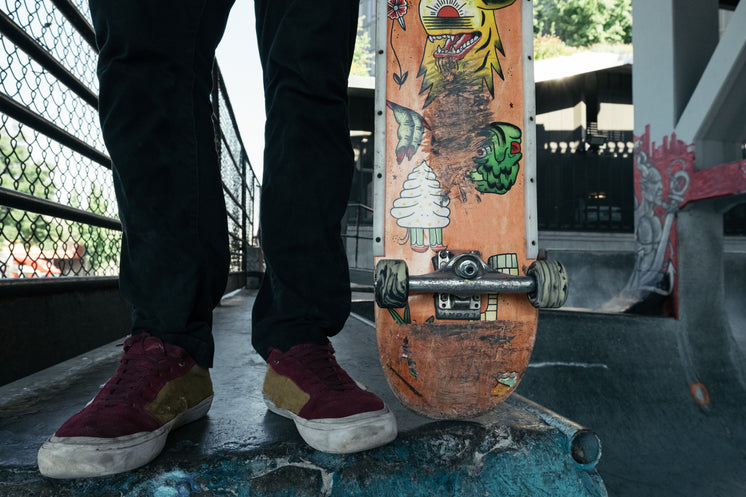 Man Stood With Skateboard Wearing Worn Sneakers