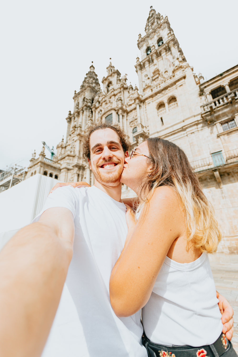 man takes selfie while a woman kisses him