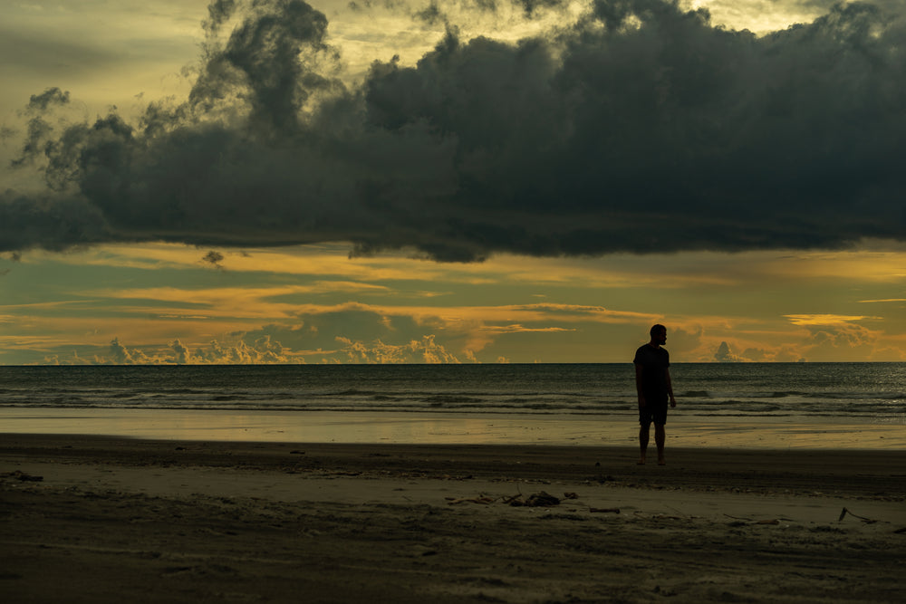 man thinking on beach at dusk