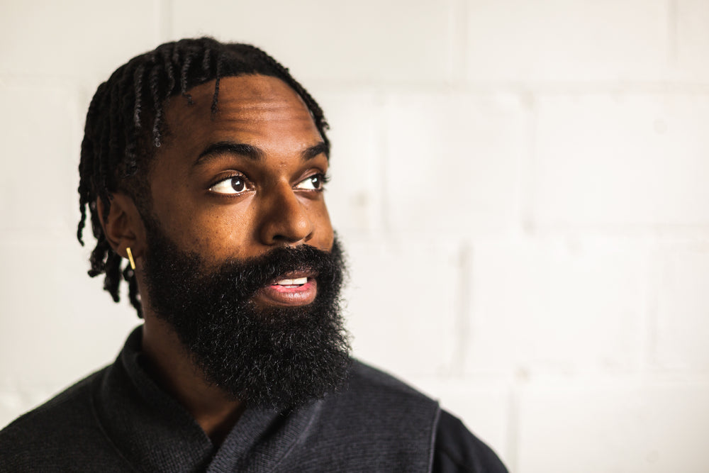 man with beard looks out of window