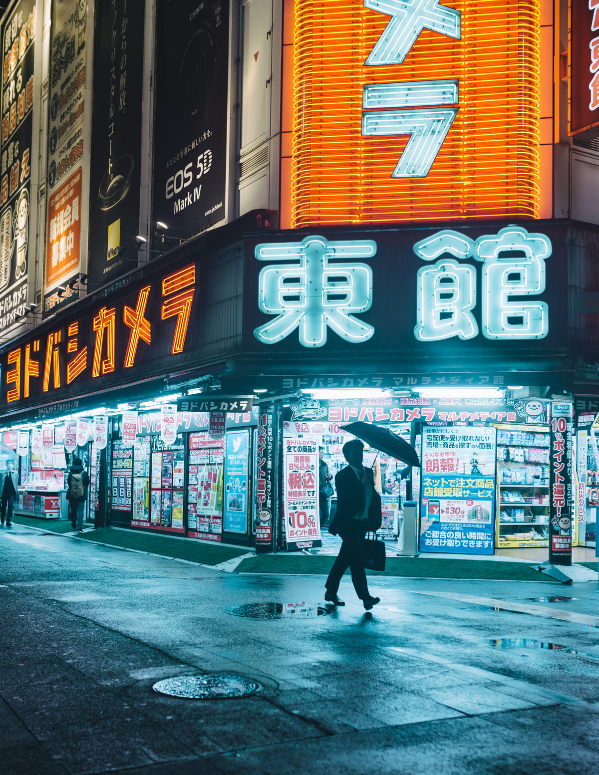 man with umbrella framed by the neon tapestry of tokyo
