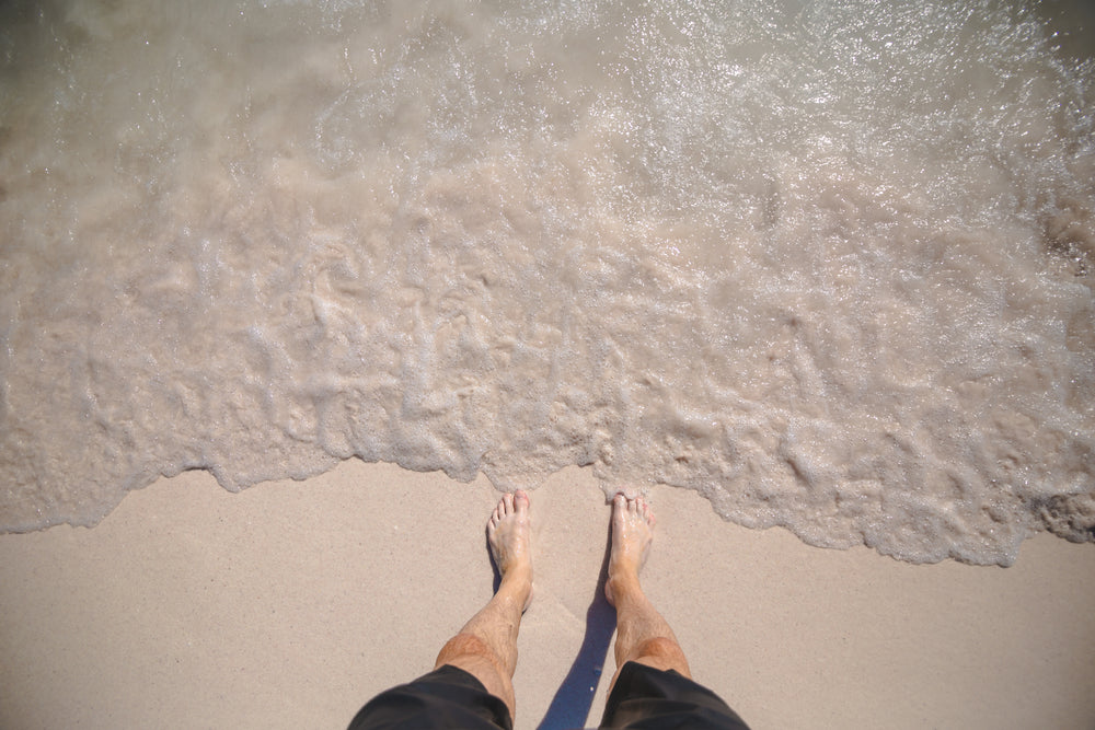 mans feet on ocean shore