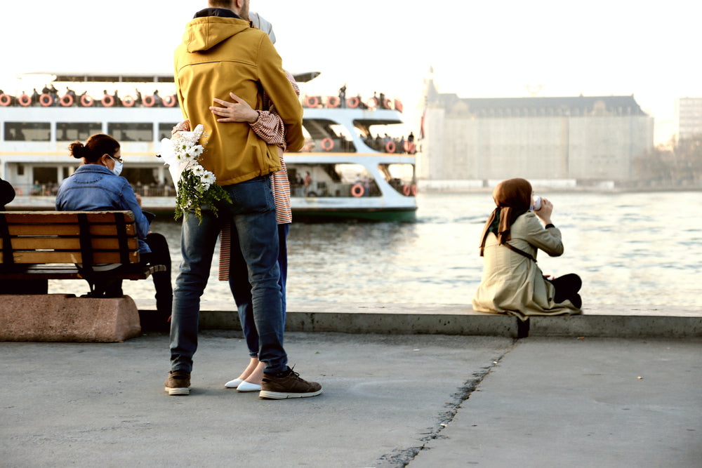 masked people on the boardwalk next to open water