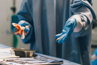 medical professional in scrubs holds bloody gauze and tools