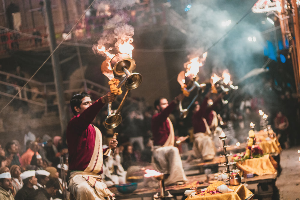 men hold an open flame above their head