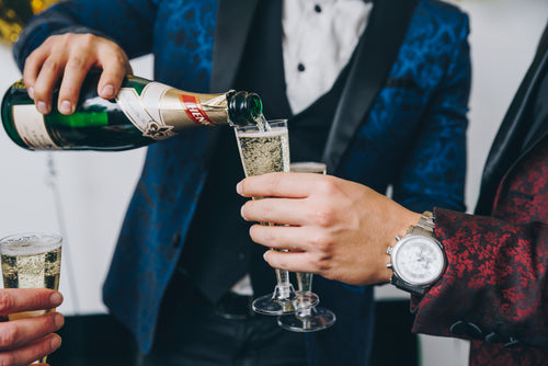 men in tuxedos pouring sparkling wine