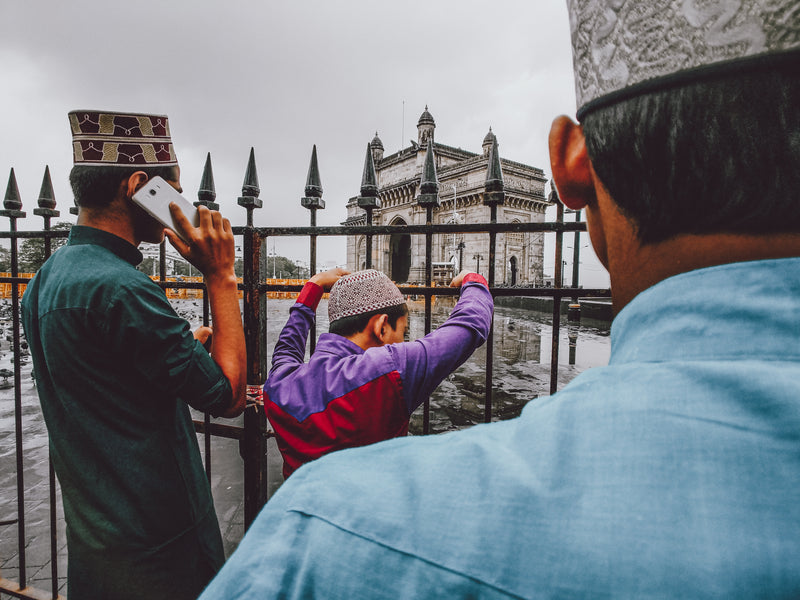 men sporting taqiyah headwear - a man taking a picture of a woman in a purple dress