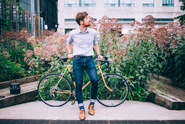 men's fashion man in shirt and jeans leaning on bicycle