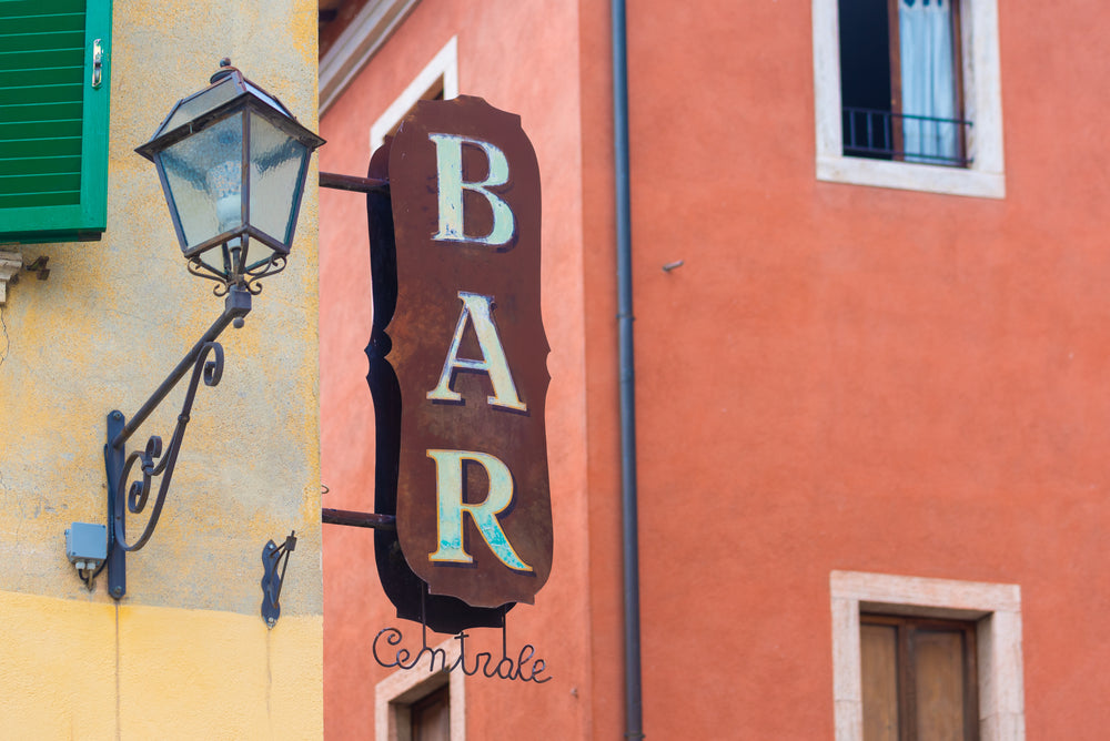 metal bar sign hanging on bright building wall